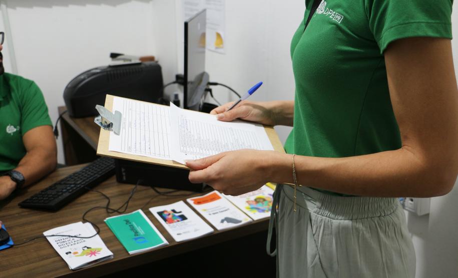 Imagem em close da servidora da DPE-PR segurando prancheta com os dados dos assistidos.