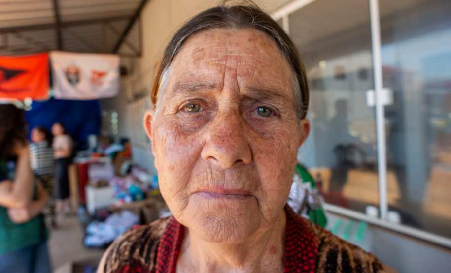 Imagem com o rosto de uma senhora olhando diretamente para a câmera que a fotografou. Ela esta séria e não demonstra nenhuma expressão.