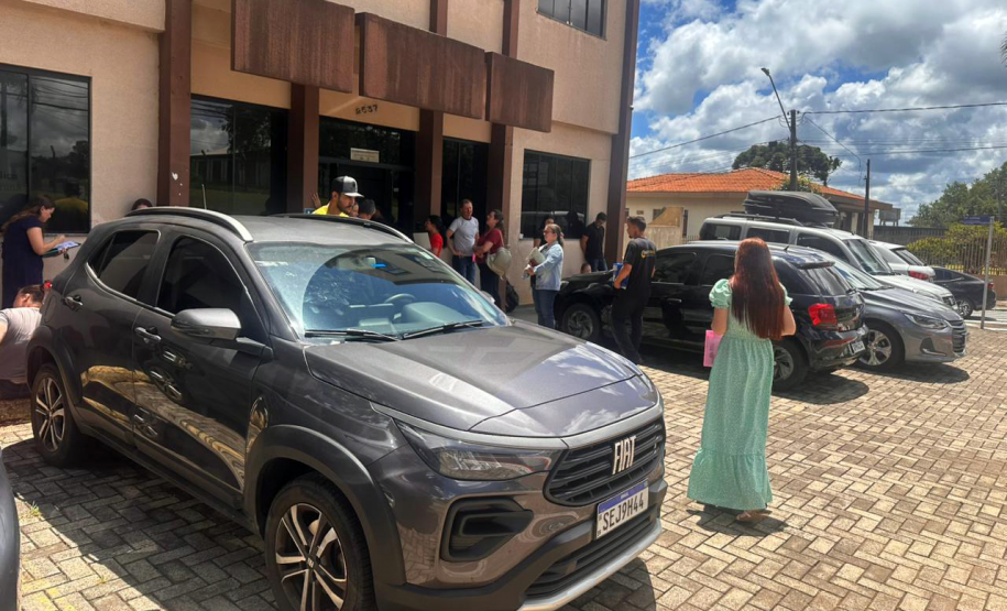 Mulher de vestido verde aparece de costas caminhando para a entrada da sede da Defensoria em Guarapuava.