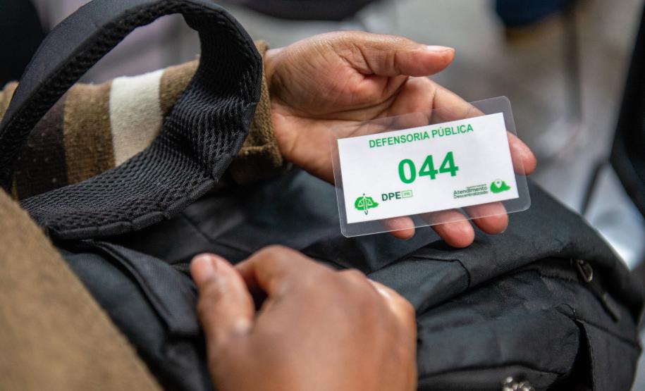 Detalhe mostra senha de atendimento na mão de assistido da DPE-PR.