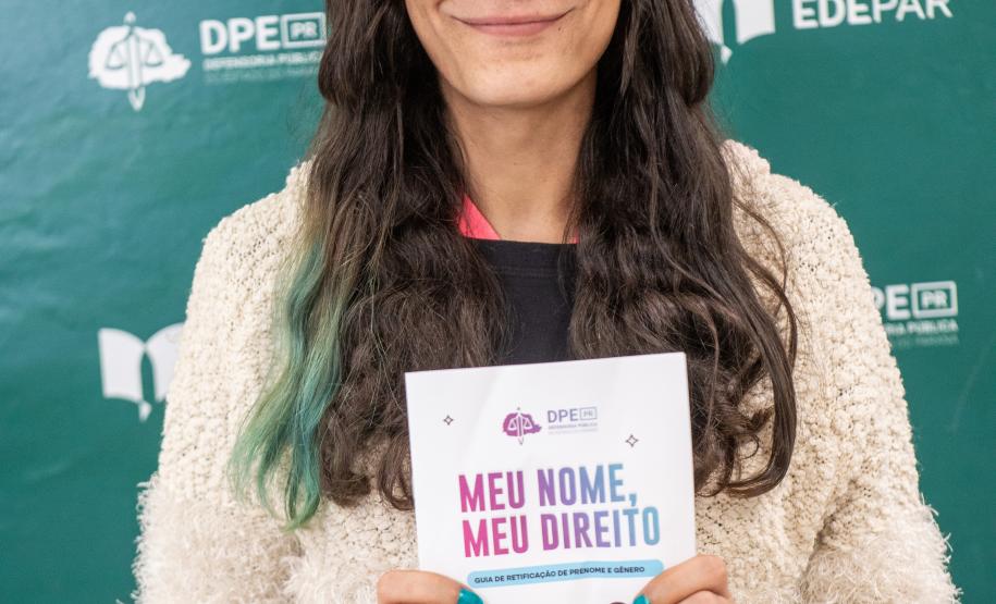 Mulher trans segura panfleto no Mutirão Meu Nome Meu Direito.