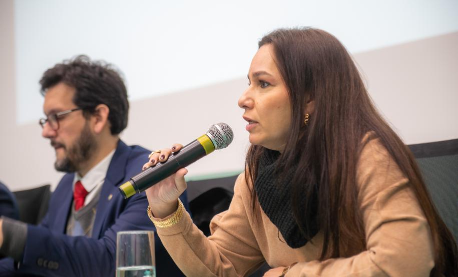 Ana Carolina Pinto fala ao microfone. Ela é Promotora de Justiça do Ministério Público do Estado do Paraná.