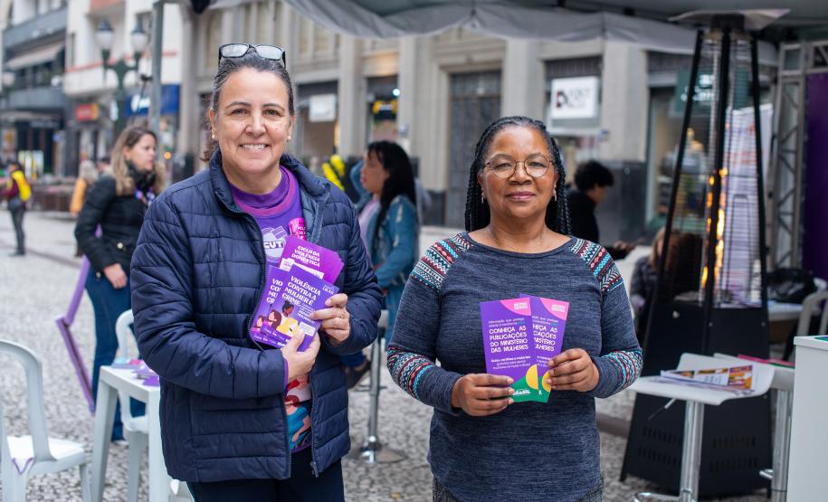 Mulheres seguram panfletos da Tenda Lilás.
