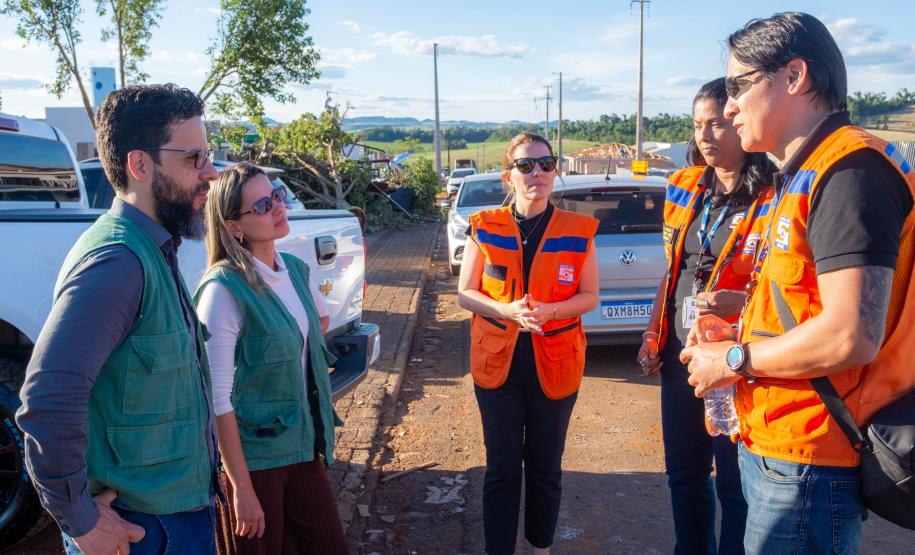 Imagem mostra a coordenadora do NUCRISE, defensora pública Ingrid Lima, conversando com as equipes da Defesa Civil do Estado.