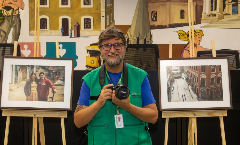 O fotógrafo Daniel Caron posa com os quadros da exposição.