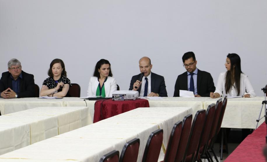Vê-se o Dr. Eduardo Abraão, Defensor Público-Geral, sentado na mesa que compôs a abertura do evento. A sua direita está sentada a Dra. Flávia Palazzi, Diretora da EDEPAR, a Assistente Social, Gabriele Rezende, e o Ouvidor-Geral, Dr. Gerson da Sllva. 
A esquerda do DPG, está sentado o presidente da ASSEDEPAR Louis Pasteur e a Psicologa Alysha Carolyna.