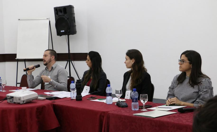 Na imagem vemos os palestrantes da mesa Mediação: Bruno Cordeiro, Psicólogo - Setor da Mediação Curitiba, Alysha Carolyna, Psicóloga - Setor da Mediação CAM Londrina, Andreia Ungari, Assistente Social do CAM Maringá e mediadora dessa mesa, e Taísa de Oliveira ,Assistente Social do CAM Curitiba. 
Todos estão sentados a mesa de palestrantes.