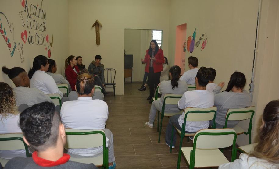 Observa-se a Dra. Cinthia Azevedo Santos palestrando no fundo de uma sala, na penitenciária feminina.