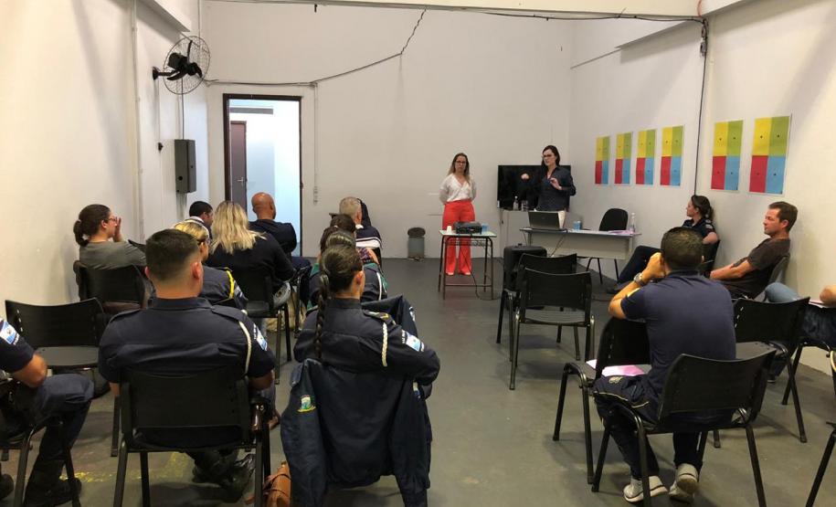 Na imagem vemos a equipe da DPPR palestrando aos guardas municipais. A equipe está de pé, ao fundo da sala, na frente dos oficias (esses estão sentados de costas).