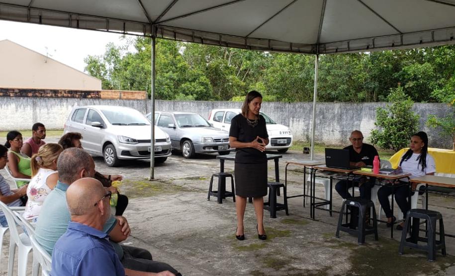 Na imagem vemos a Dra. Olenka Lins cercada por diversas pessoas sentadas em formato de roda.