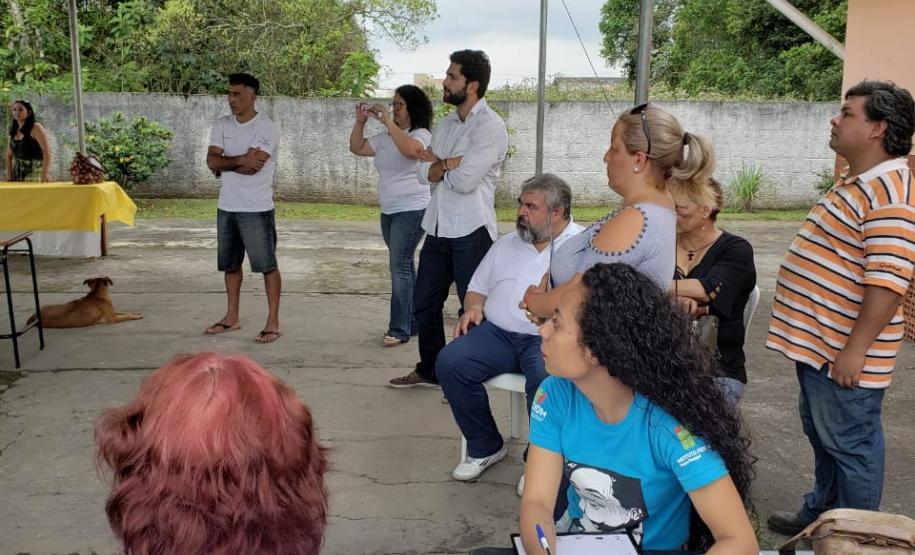 Na imagem vemos algumas pessoas e outras em pé prestando atenção em algo que é dito por uma pessoa fora do quadro da imagem.