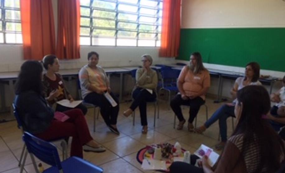 O grupo de responsáveis se encontra em formato de roda, todos sentados em cadeiras, conversando.
