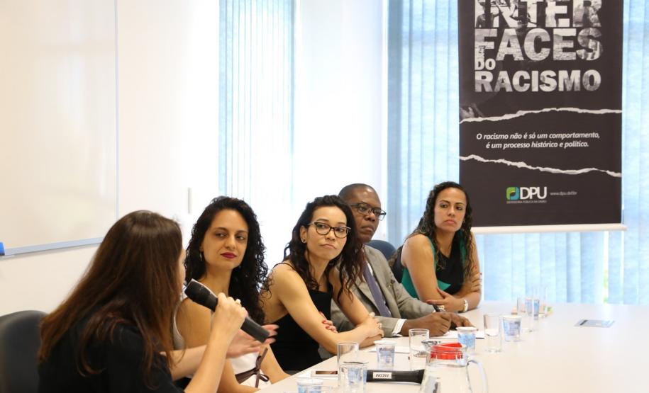 Na imagem vemos a mesa de abertura do evento e ao fundo é visível o cartaz de divulgação do evento.