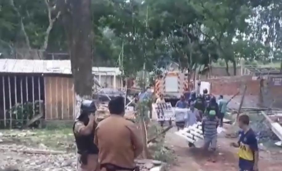 Imagem da reintegração de posse. Policiais no canto esquerdo da foto, no direito estão as pessoas desabrigadas carregando suas coisas.