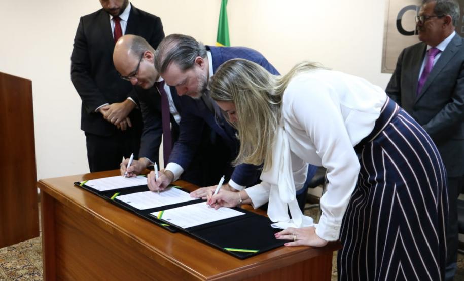 Mariana Lobo, defensora geral do Ceará no canto direito da imagem, Ministro Dias Toffoli, presidente do STF e do CNJ, no meio; e o defensor geral do Paraná, Eduardo Abraão, no canto esquerdo. Os três estão assinando o termo de cooperação.