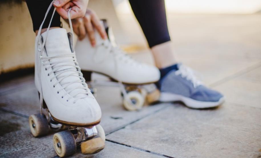 Imagem de uma menina sentada segurando laços de patins de rodas