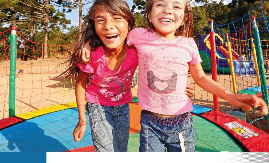 #LegendaAcessível: A imagem apresenta duas crianças abraçadas e felizes pulando em uma cama elástica com pinheiros e um lindo céu azul de fundo.

No rodapé no canto esquerdo a data 24 Agosto, Dia da Infância e no canto direito a logo da DPE-PR