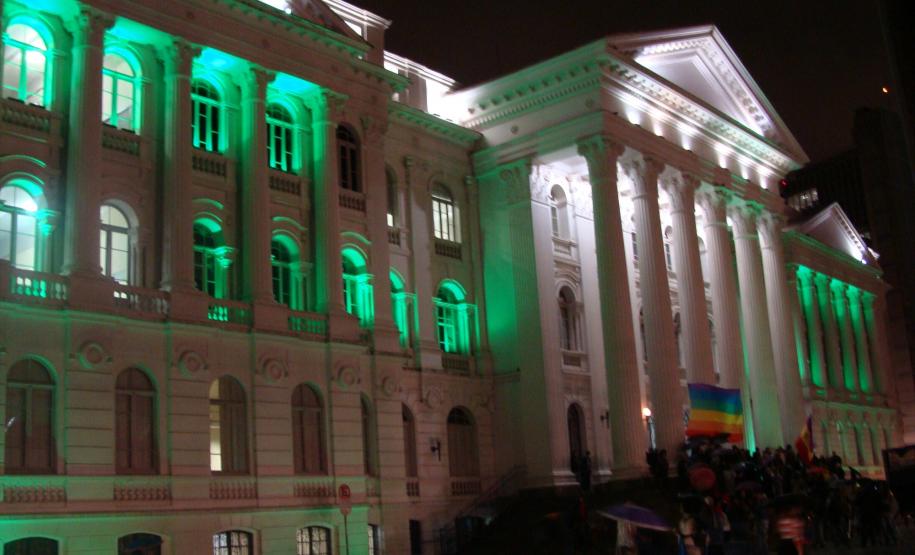 Fachada da Universidade Federal do Paraná iluminada de verde, a cor que simboliza a Defensoria Pública.