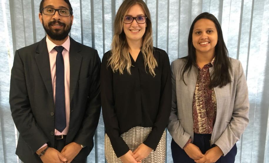 Estão na foto, da esquerda para a direita: o defensor público auxiliar do Núcleo Wisley Rodrigo dos Santos,  a defensora pública de Direitos Humanos da Regional Paraná/ Santa Catarina, Carolina Balbinott Bunhak e a coordenadora do Núcleo da Cidadania e Direitos Humanos da Defensoria Pública do Paraná (NUCIDH) Cinthia Azevedo Santos. Os três estão olhando para a lente da câmera.